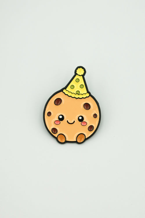cookiegrips 1st Anniversary Enamel Pin with cookie mascot wearing a yellow party hat