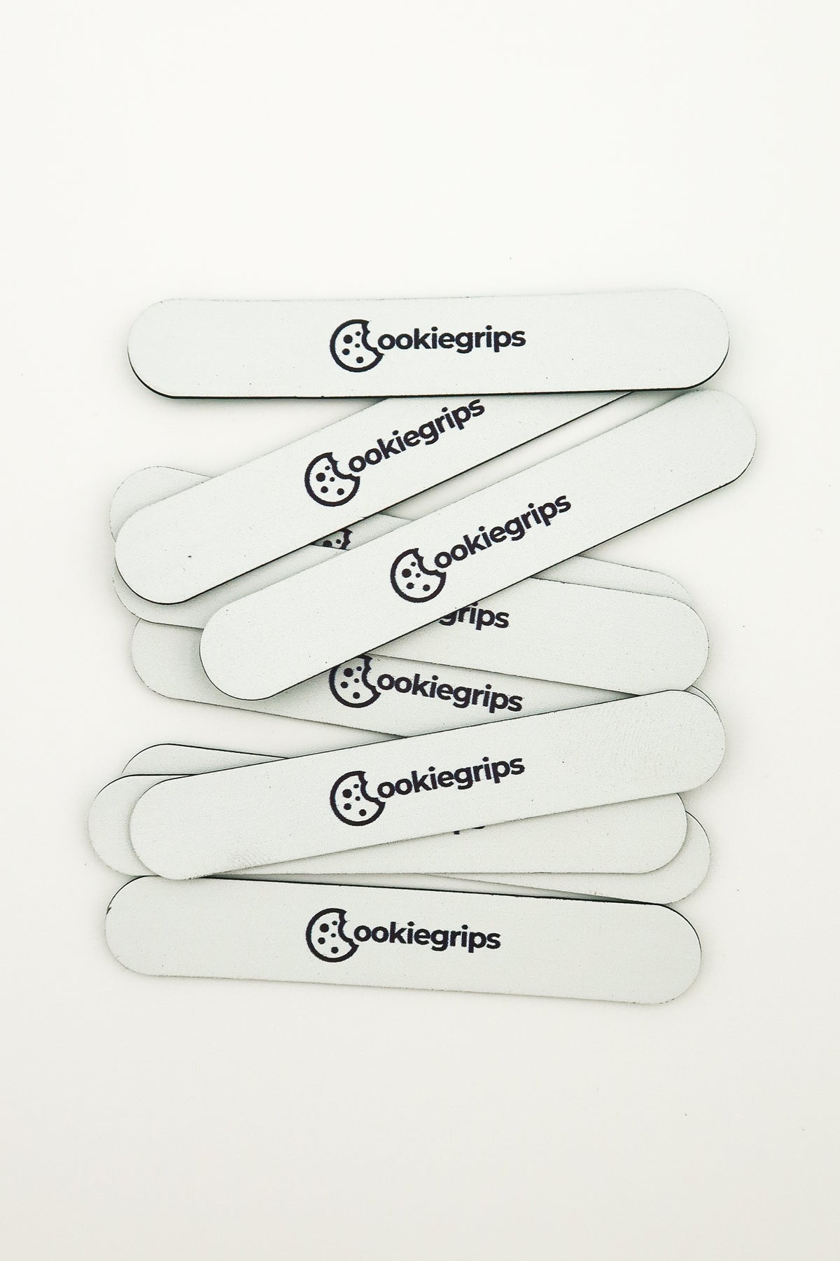 Pile of 3g Batter Bites tuning strips, Sugar Glaze white with rounded ends and the cookiegrips logo