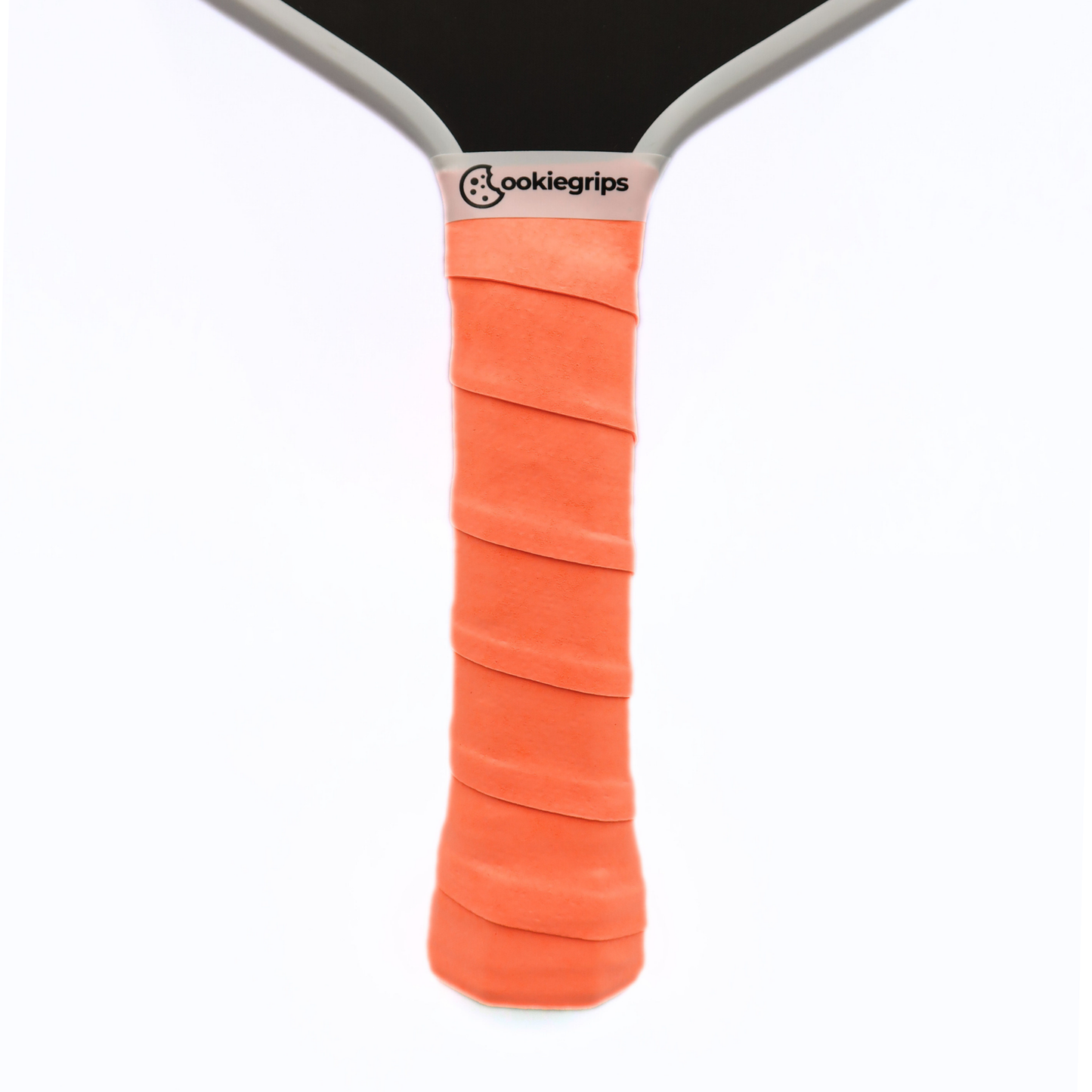 Cookiegrips Tough Cookie pickleball paddle handle wrapped with orange overgrip, showing textured dry grip and clean white paddle throat.