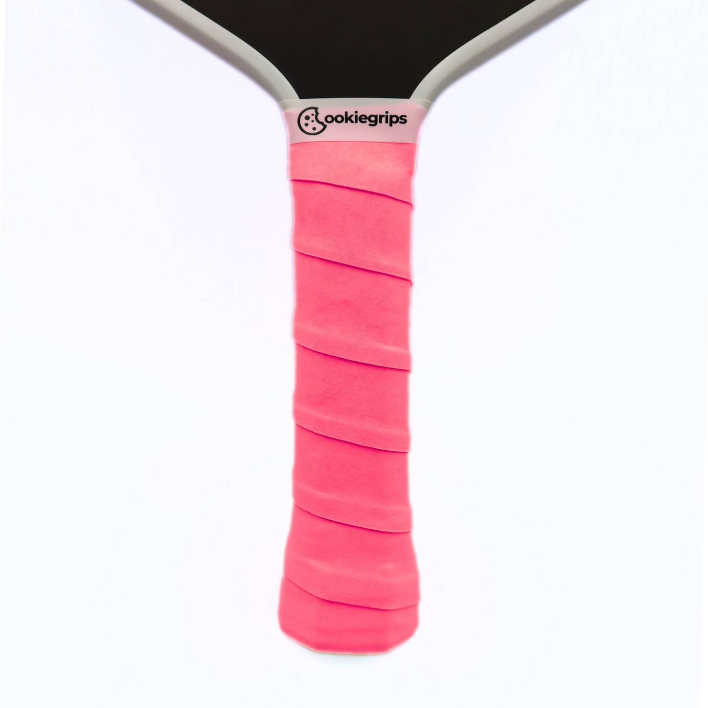 Cookiegrips Tough Cookie pickleball paddle handle wrapped with pink overgrip, showing textured dry grip and clean white paddle throat.